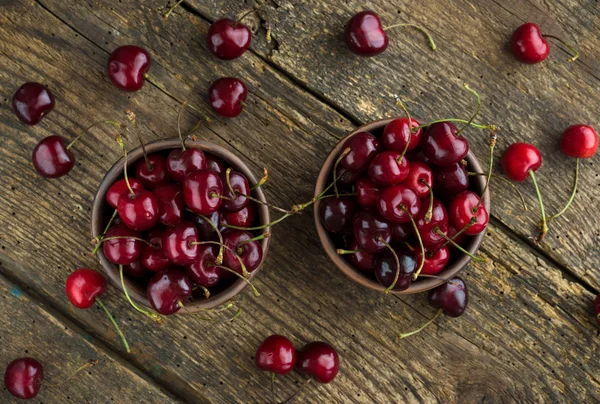 Ripe cherries in a clay bowl on a  wooden background — Stock Photo, Image