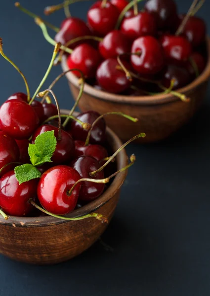 Ripe cherries in a clay bowl on black background — Stock Photo, Image