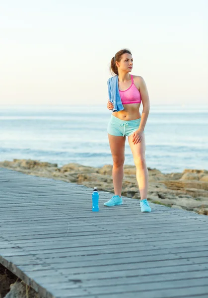 Sonniger Morgen am Strand, athletische Frau ruht sich nach dem Laufen aus — Stockfoto