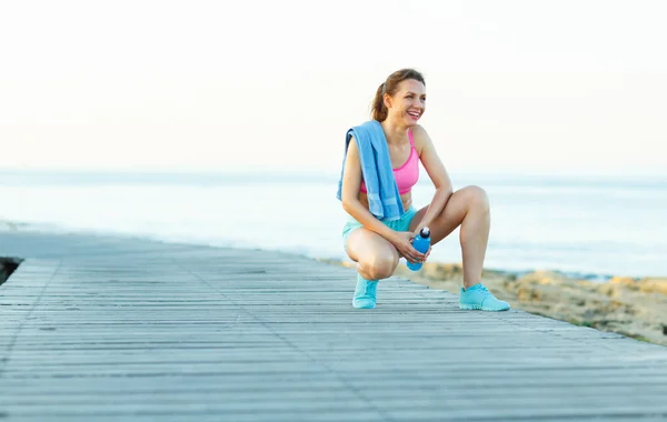 Sonniger Morgen am Strand, athletische Frau ruht sich nach dem Laufen aus — Stockfoto