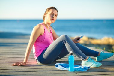 Deniz kenarındaki ahşap bir yolda koşu sonra istirahat kadın