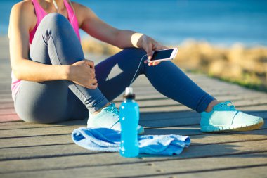 Deniz kenarındaki ahşap bir yolda koşu sonra istirahat kadın