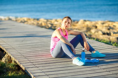 Deniz kenarındaki ahşap bir yolda koşu sonra istirahat kadın