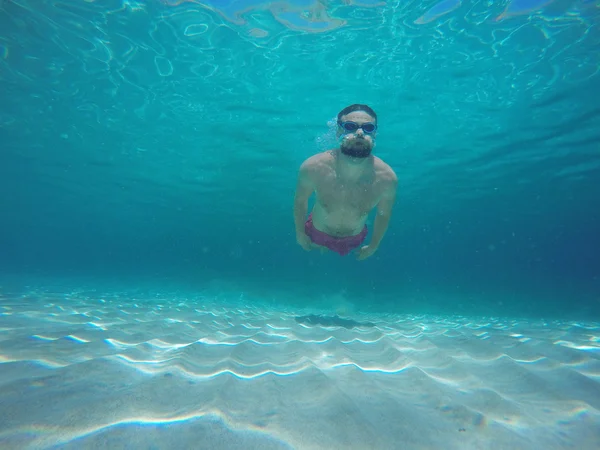 Pemuda berjanggut dengan kacamata menyelam dalam air bersih biru — Stok Foto