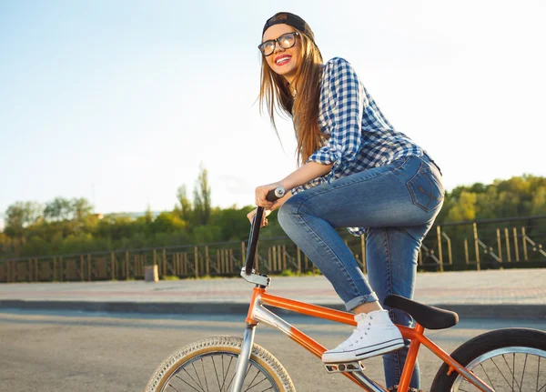 Menina encantadora em um chapéu andando de bicicleta na luz do sol ao ar livre — Fotografia de Stock