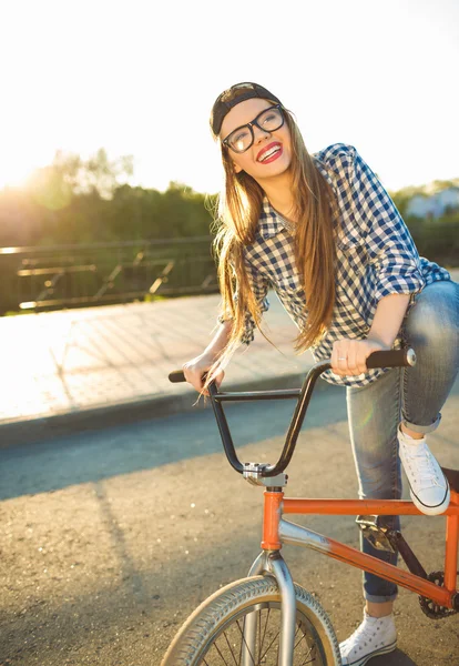 Preciosa chica en un sombrero montando una bicicleta a la luz del sol al aire libre —  Fotos de Stock