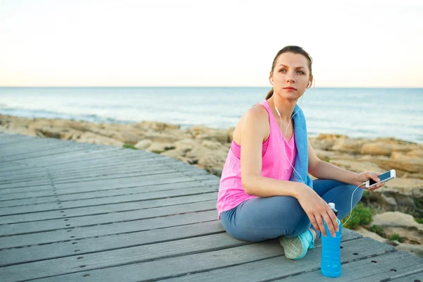 Frau rastet nach Joggen auf Holzweg am Meer aus — Stockfoto