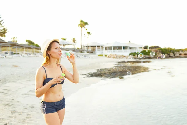Youngwoman blåser såpbubblor på havsstranden — Stockfoto