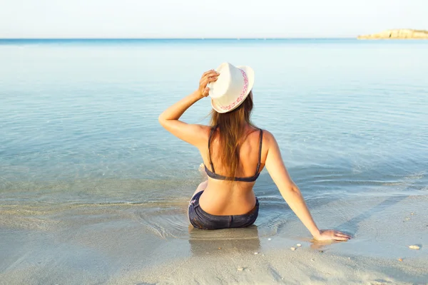 Beach Tatil. Bir şapka ve bikini b üzerinde oturan genç kadın — Stok fotoğraf