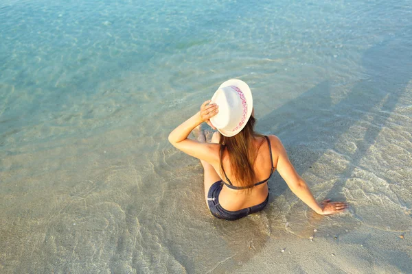 Beach Tatil. Bir şapka ve bikini b üzerinde oturan genç kadın — Stok fotoğraf