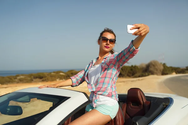 Mujer joven en gafas de sol haciendo autorretrato sentado en la ca — Foto de Stock