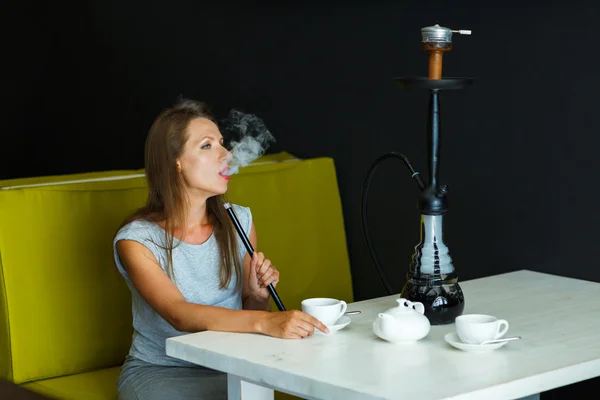 Vacker kvinna röka vattenpipa och dricka te i ett café — Stockfoto