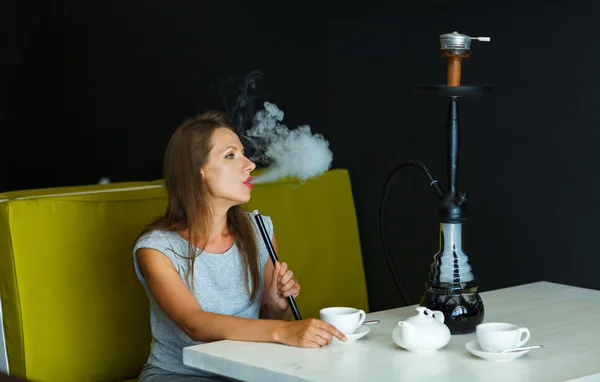 Mulher bonita fumando um narguilé e bebendo chá em um café — Fotografia de Stock