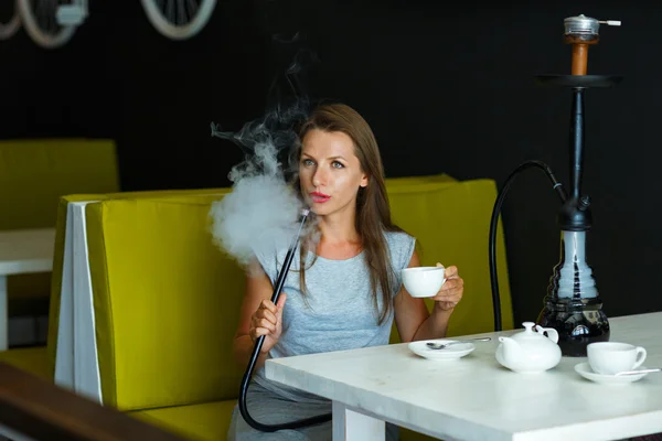 Όμορφη γυναίκα κάπνισμα ναργιλέ και πίνοντας τσάι σε ένα καφέ — Φωτογραφία Αρχείου
