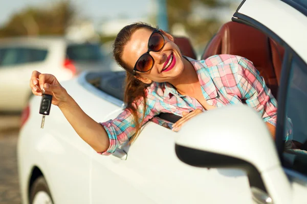 Jovem mulher bonita sentada em um carro conversível com as chaves em — Fotografia de Stock