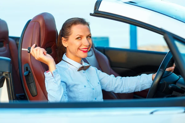 Joven mujer bonita sentada en un coche descapotable con las llaves en —  Fotos de Stock