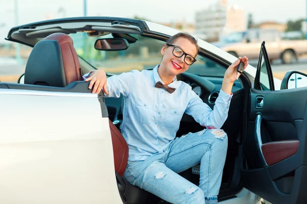 Mladá krásná žena sedí v autě, kabriolet s klíči v — Stock fotografie