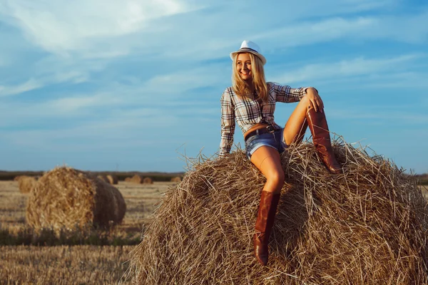 Mooie mode vrouw in koe meisje landelijke stijl op stapel hooi — Stockfoto