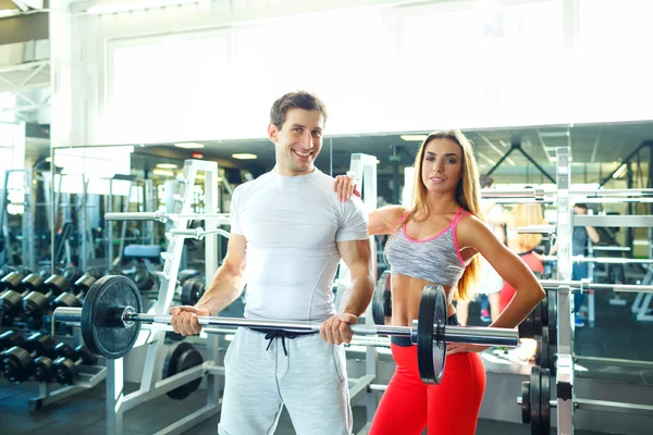 健壮的男人和女人与杠铃锻炼在健身房里 — 图库照片