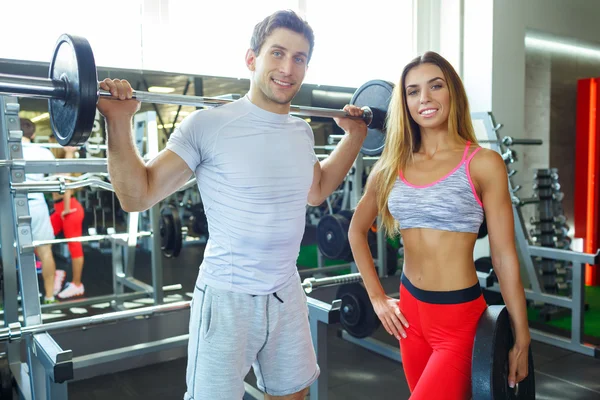Atlético homem e mulher com barbell fazendo exercícios no ginásio — Fotografia de Stock