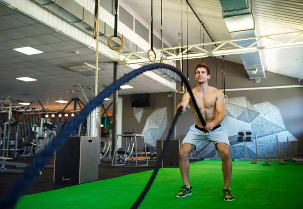 Hombre con cuerda de batalla en gimnasio de entrenamiento funcional — Foto de Stock