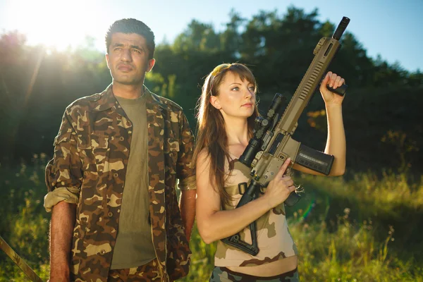 Witte meisje en een Arabische man in camouflage met een wapen in de ha — Stockfoto