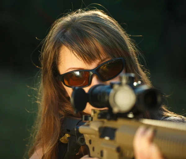 Girl with a gun for trap shooting and shooting glasses aiming at — Stock Photo, Image