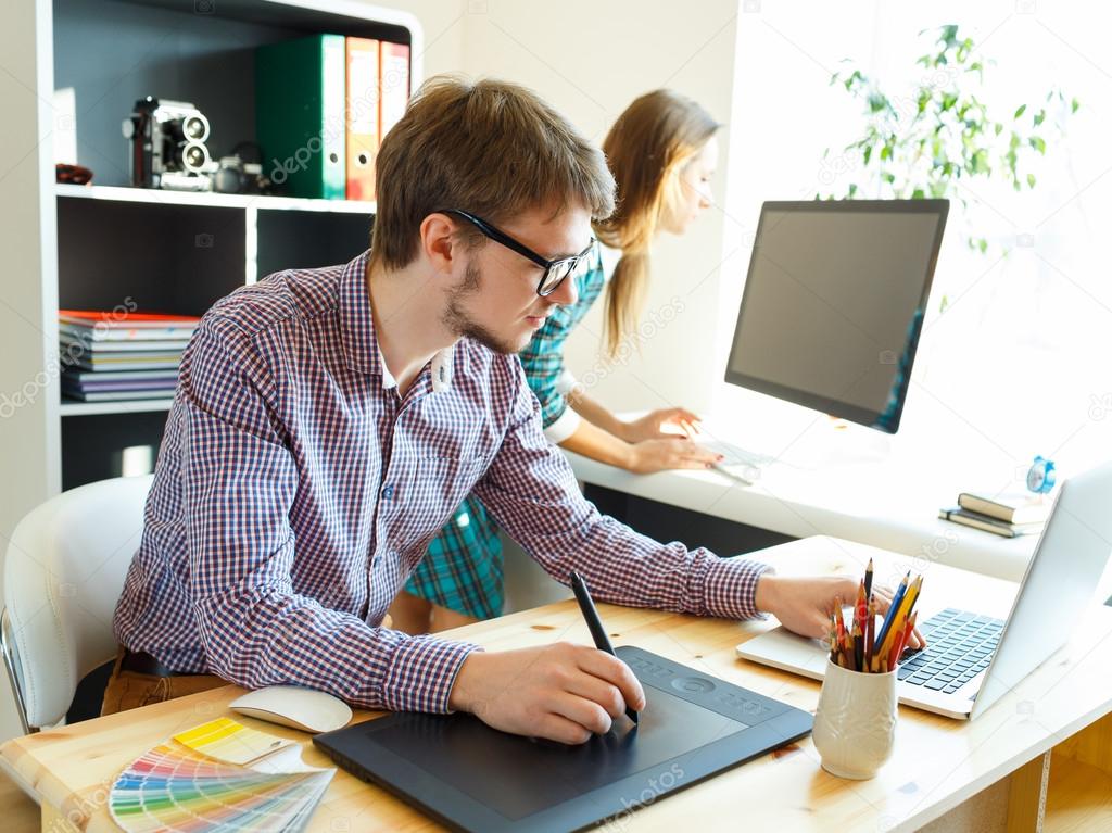 Young artist drawing something on graphic tablet at the office