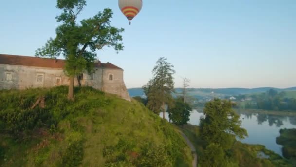 Balões de ar quente coloridos voam sobre o castelo medieval e lago no nevoeiro da manhã. Voo manobrável. Viagens, aventura, festival. — Vídeo de Stock