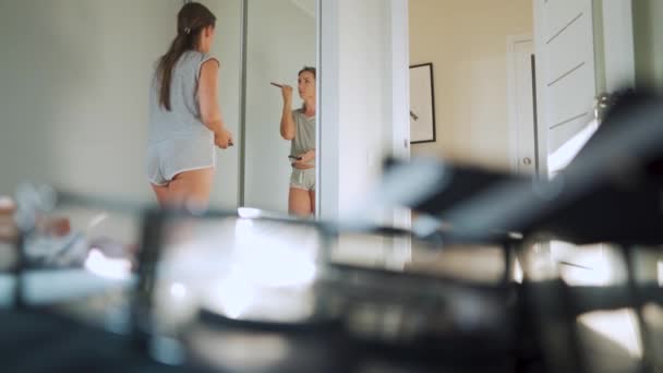 Vrouw staat voor een spiegel en brengt make-up op haar gezicht — Stockvideo