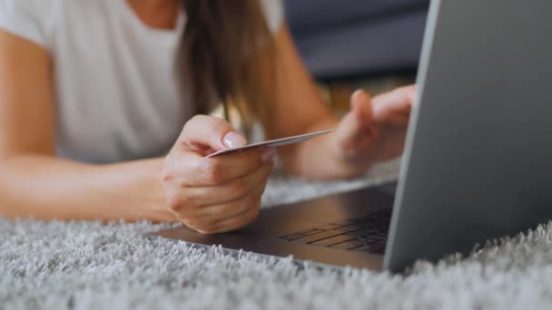 Kobieta leży na podłodze i dokonuje zakupu online za pomocą karty kredytowej i laptopa. Zakupy online, technologia stylu życia — Wideo stockowe