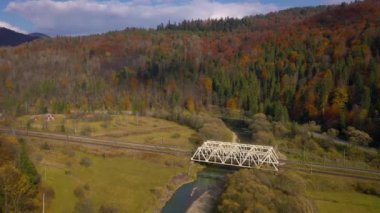 Sonbahar dağ manzarasının yüksekliğinden manzara - sarı orman, nehir, demiryolu köprüsü ve yol trafiği
