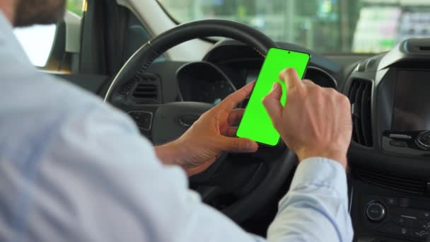 차 안에서 스마트폰을 사용하는 운전자. 녹색 화면을 가진 크로마키 스마트폰입니다. 자동 항법 장치. 인터넷 중독 — 비디오