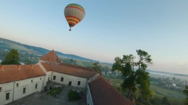 Bunte Heißluftballons fliegen im Morgennebel über die mittelalterliche Burg und den See. Manövrierbarer Flug. Reisen, Abenteuer, Festival. — Stockvideo