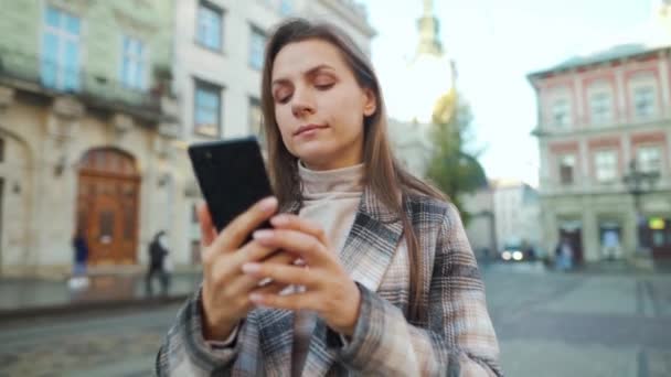Mulher andando por uma rua velha e usando smartphone, tirando fotos de edifícios ao redor — Vídeo de Stock