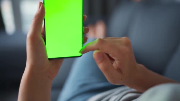 Frau zu Hause auf dem Sofa liegend und Smartphone mit grünem Bildschirm im vertikalen Modus. Mädchen surfen im Internet, schauen sich Inhalte, Videos, Blogs an. POV. — Stockvideo