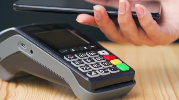 Contactless payment with smartphone. Wireless payment concept. Close-up, woman using smartphone cashless wallet NFC technology to pay order on bank terminal. — Stock Video