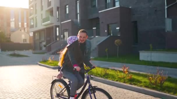 Tata uczy córkę jeździć na rowerze o zachodzie słońca. — Wideo stockowe