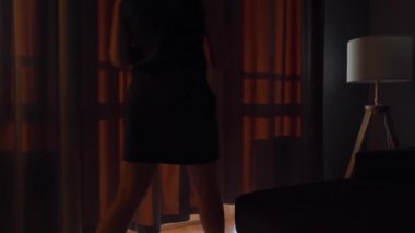 Kadın, güneş ışığını odaya almak için perdeleri açar.