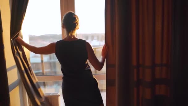 Γυναίκα ανοίγει κουρτίνες για να αφήσει το φως του ήλιου στο δωμάτιο — Αρχείο Βίντεο
