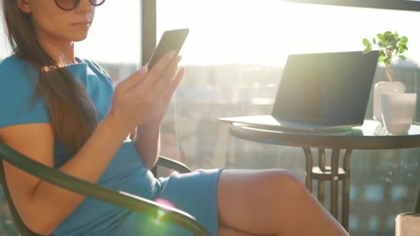 Γυναίκα που χρησιμοποιεί smartphone στο μπαλκόνι με φόντο το ηλιοβασίλεμα. Εξωτερικό γραφείο. Έννοια απομακρυσμένης εργασίας — Αρχείο Βίντεο