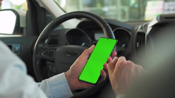 Řidič používá v autě smartphone. Chromakey smartphone se zelenou obrazovkou. Autonavigace. Internetová závislost — Stock video