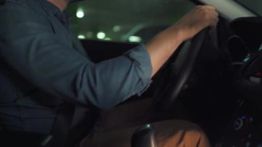 Adam yeraltı otoparkında araba sürüyor ve park edecek bir yer arıyor. Yan görünüm