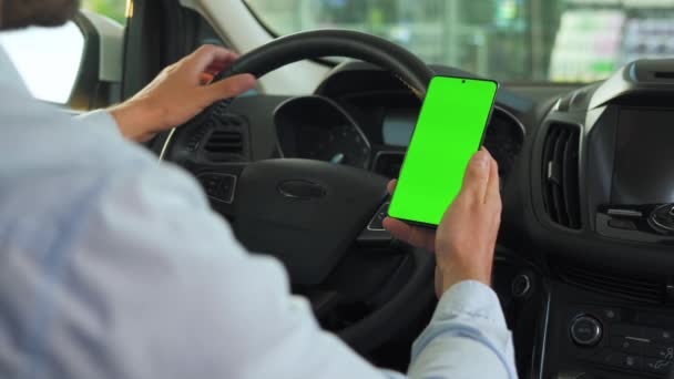Motorista usando um smartphone dentro do carro. Smartphone Chromakey com tela verde. Navegação automática. Vício em Internet — Vídeo de Stock