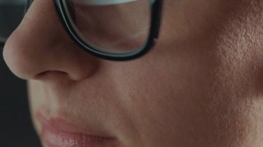 Gözlüklü kadın monitöre bakıyor ve internette sörf yapıyor. Monitör ekranı gözlüklere yansıyor. Gece çalış. İçişleri Bakanlığı. Uzak çalışma