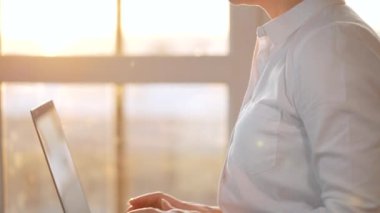 Gün batımına karşı dizüstü bilgisayarda çalışan yakın plan kadın. Uzak çalışma kavramı.