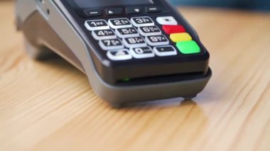 Akıllı telefondan yapılan temassız ödeme. Kablosuz ödeme konsepti. Yakın plan, kadın banka terminalindeki siparişi ödemek için akıllı telefon nakitsiz cüzdan teknolojisi kullanıyor..