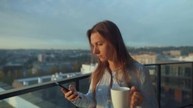 Kadın güne bir fincan çay ya da kahveyle başlıyor ve şafak vakti balkondaki akıllı telefonundaki e-postaları kontrol ediyor..