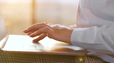 Gün batımına karşı dizüstü bilgisayarda çalışan yakın plan kadın. Uzak çalışma kavramı.