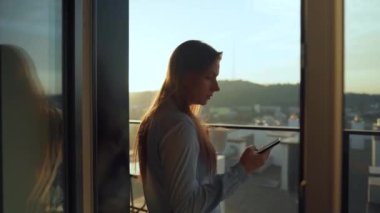 Kadın güne bir fincan çay ya da kahveyle başlıyor ve şafak vakti balkondaki akıllı telefonundaki e-postaları kontrol ediyor..